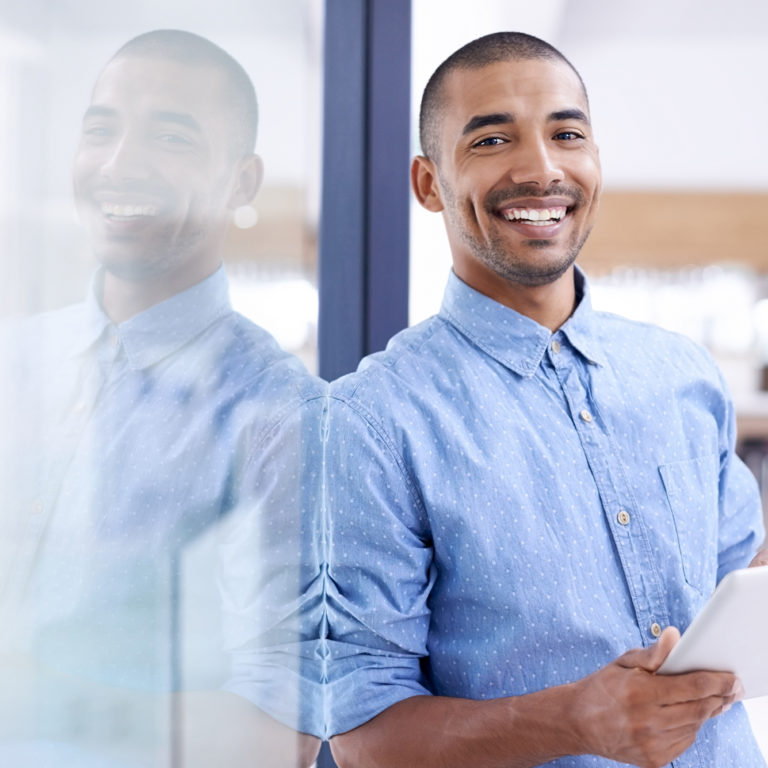 Man Smiling and Holding a Tablet in Office Space